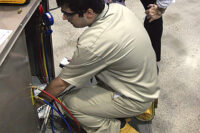 Procedures for proper refrigerant recovery and recycling are undertaken by a 2014 SkillsUSA National Championship contestant under the watchful eye of judge Warren Lupson.