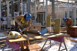 Insulators cut sheet metal for placement around large pipes at a project in southeastern Colorado. 