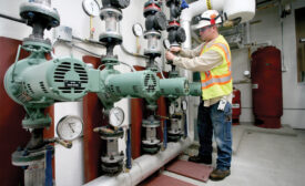 Steve Bothell, WeldinÃ¢â¬â¢s lead foreman, attaches a pump pressure gauge to one of the main Taco LoadMatch pumps for the two 3-inch primary mains at this Professional Military Education Center.