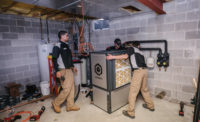 Vertex mechanical technicians move the 4-ton Q Energy ground source heat pump into place during a retrofit. - The ACHR News