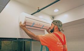 An HVAC tech installs a ductless unit in the ceiling of a Cornish Pasty restaurant.