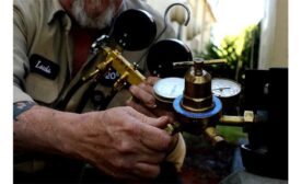 A technician checks the refrigerant pressure in an air conditioning condenser.