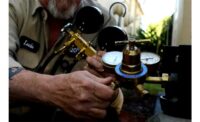 A technician checks the refrigerant pressure in an air conditioning condenser.